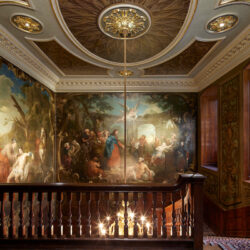 The view from the top of Hogarth Stair at Barts North Wing, showing his paintings illuminated by a central chandelier.