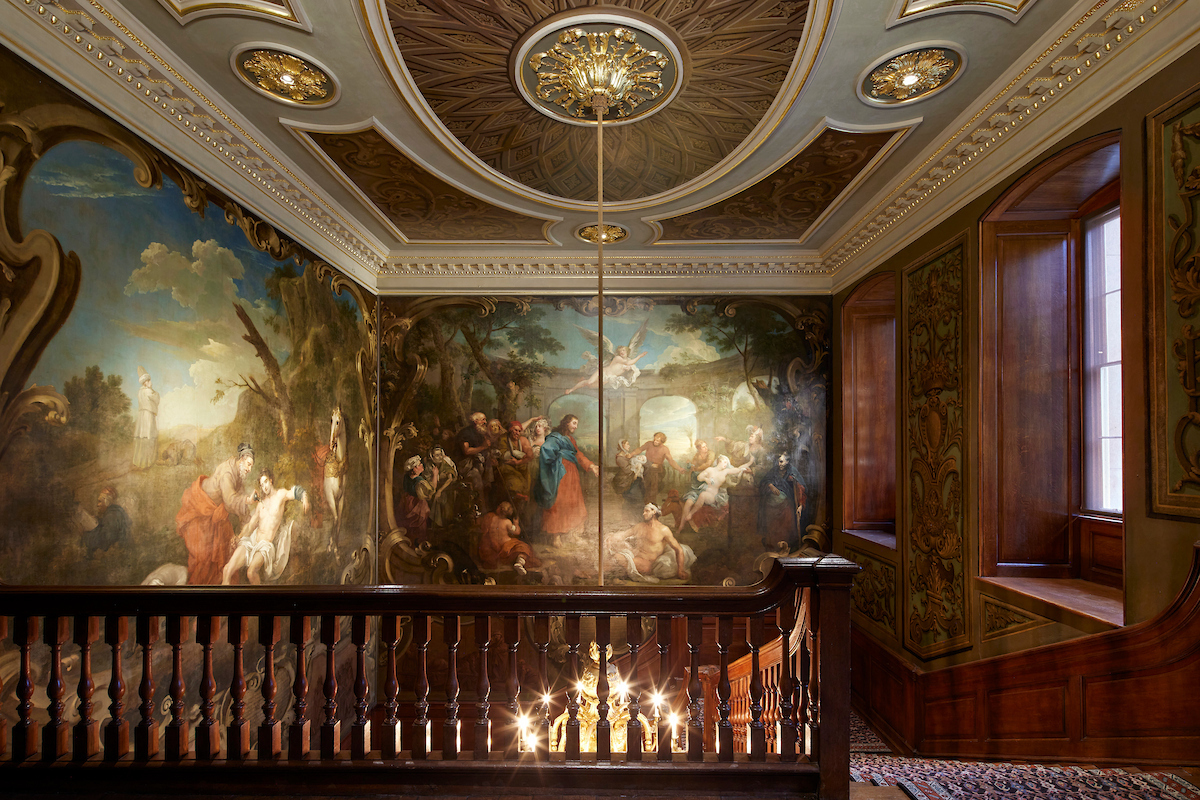 The view from the top of Hogarth Stair at Barts North Wing, showing his paintings illuminated by a central chandelier.