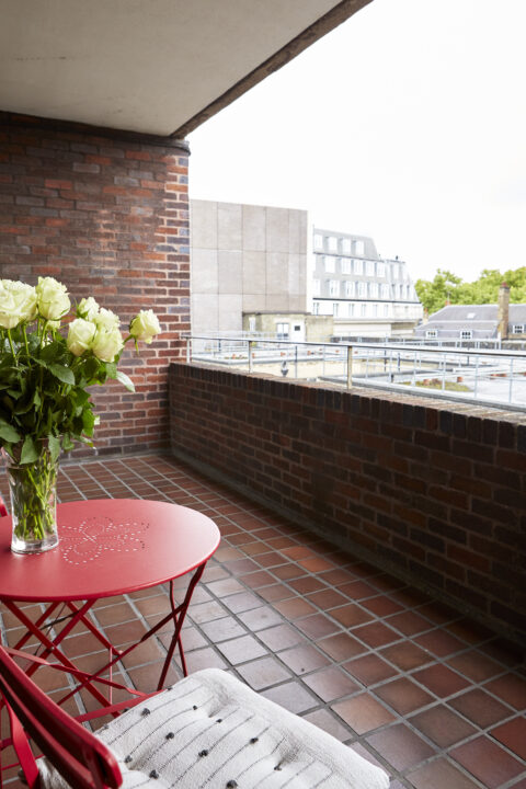 Tile and brick balcony with red table and chairs, with view towards Piccadilly and Green Park.