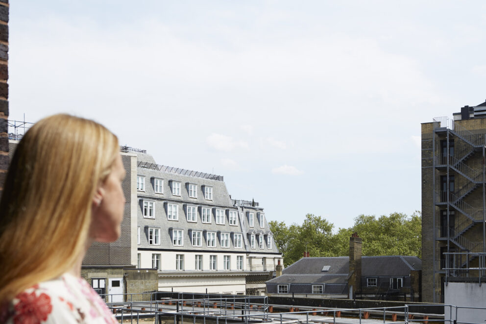 A guest looking at the view of buildings and trees from the balcony.