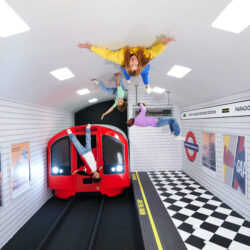 An area of the Paradox Museum in London which shows the recreation of a London underground station with a train, and visitors on the ceiling.
