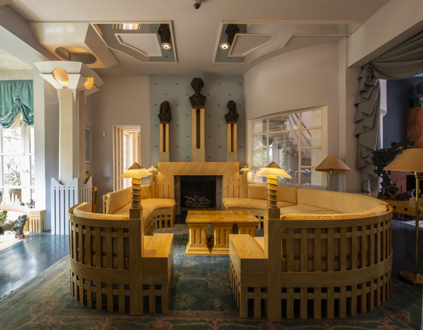 The Spring Room of The Cosmic House with curved wooden seating, fireplace and bay.