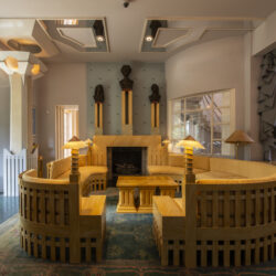 The Spring Room of The Cosmic House with curved wooden seating, fireplace and bay.