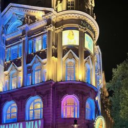 The Novello Theatre at night time, lit up in pink and white lights.