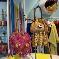 Two sea creature themed bags - one pink and one yellow - hang on a display stand in the Dive Shop, Chelsea.