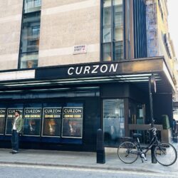 The concrete and black exterior of the Curzon Mayfair cinema with a visitor standing outside.