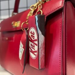 A red Anya Hindmarch bag with KitKat and Heinz Tomato Ketchup accessories.