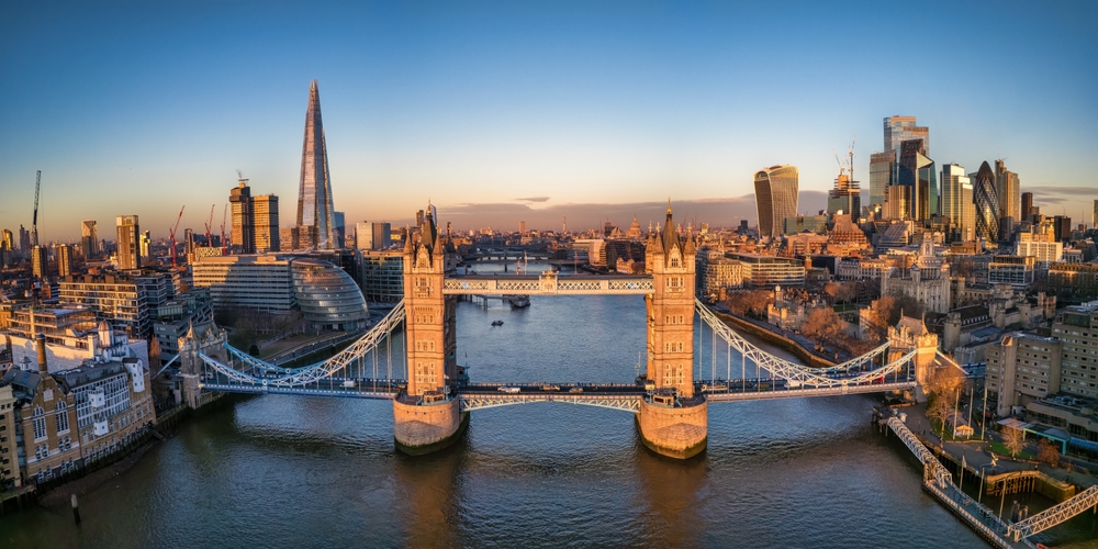 The London skyline, taken from above the Thames near Tower Bridge with iconic structures like the Shard in the distance.