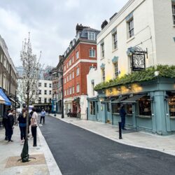 A street in Shepherd Market with canopied shops, a traditional pub and pedestrians.